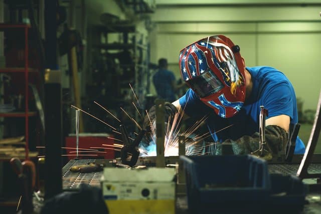 Professional heavy industry welder working inside factory